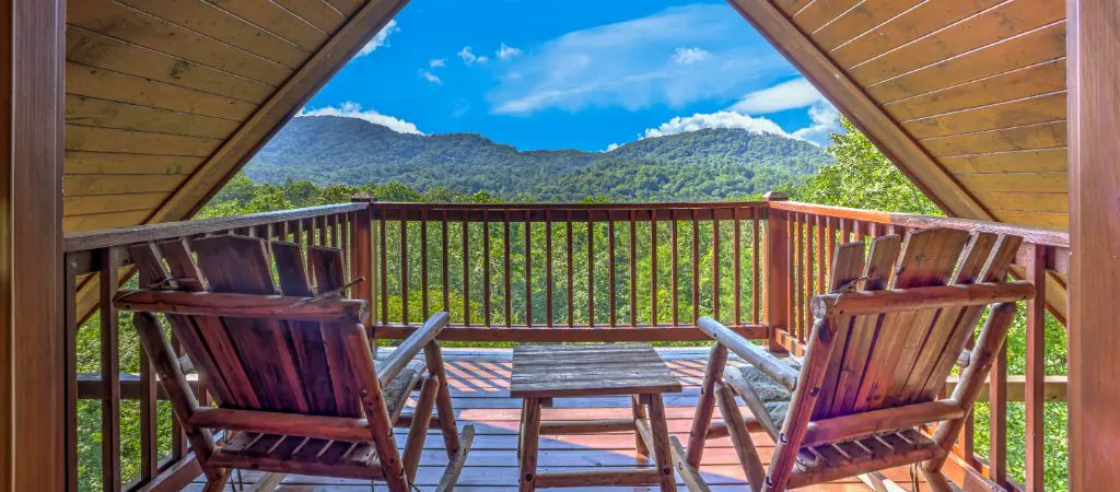 Two rocking chairs face a beautiful Blue Ridge Mountain view from a balcony at a North Georgia cabin rental.