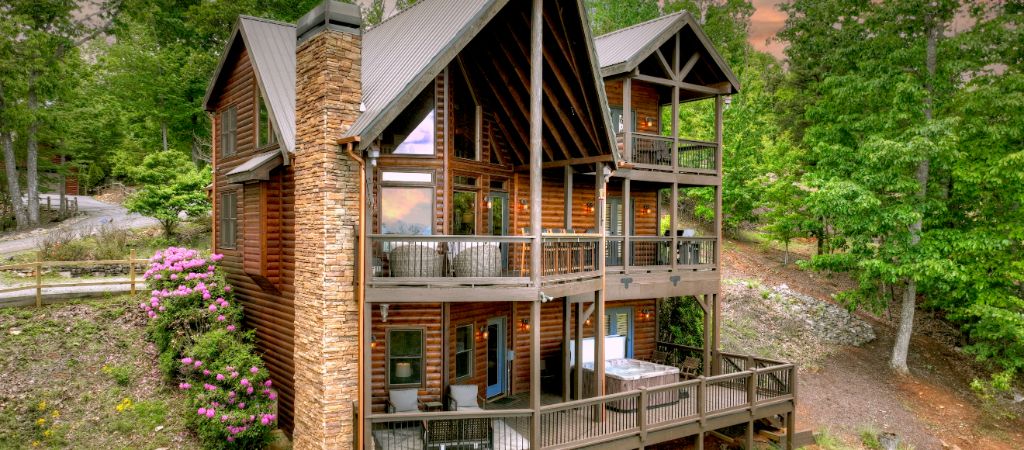 An exterior shot of a luxury log cabin in the trees.